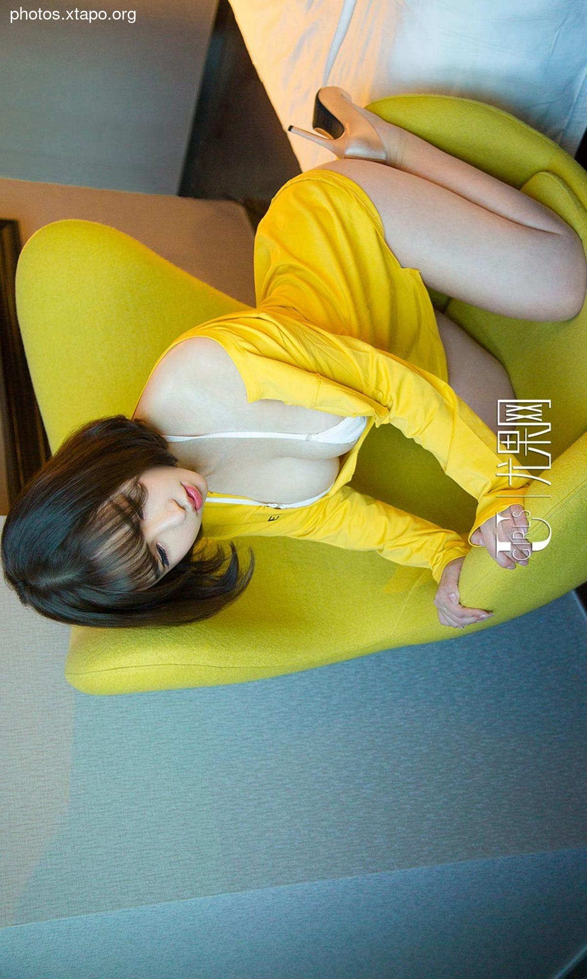 A woman in a yellow dress poses on a yellow chair.