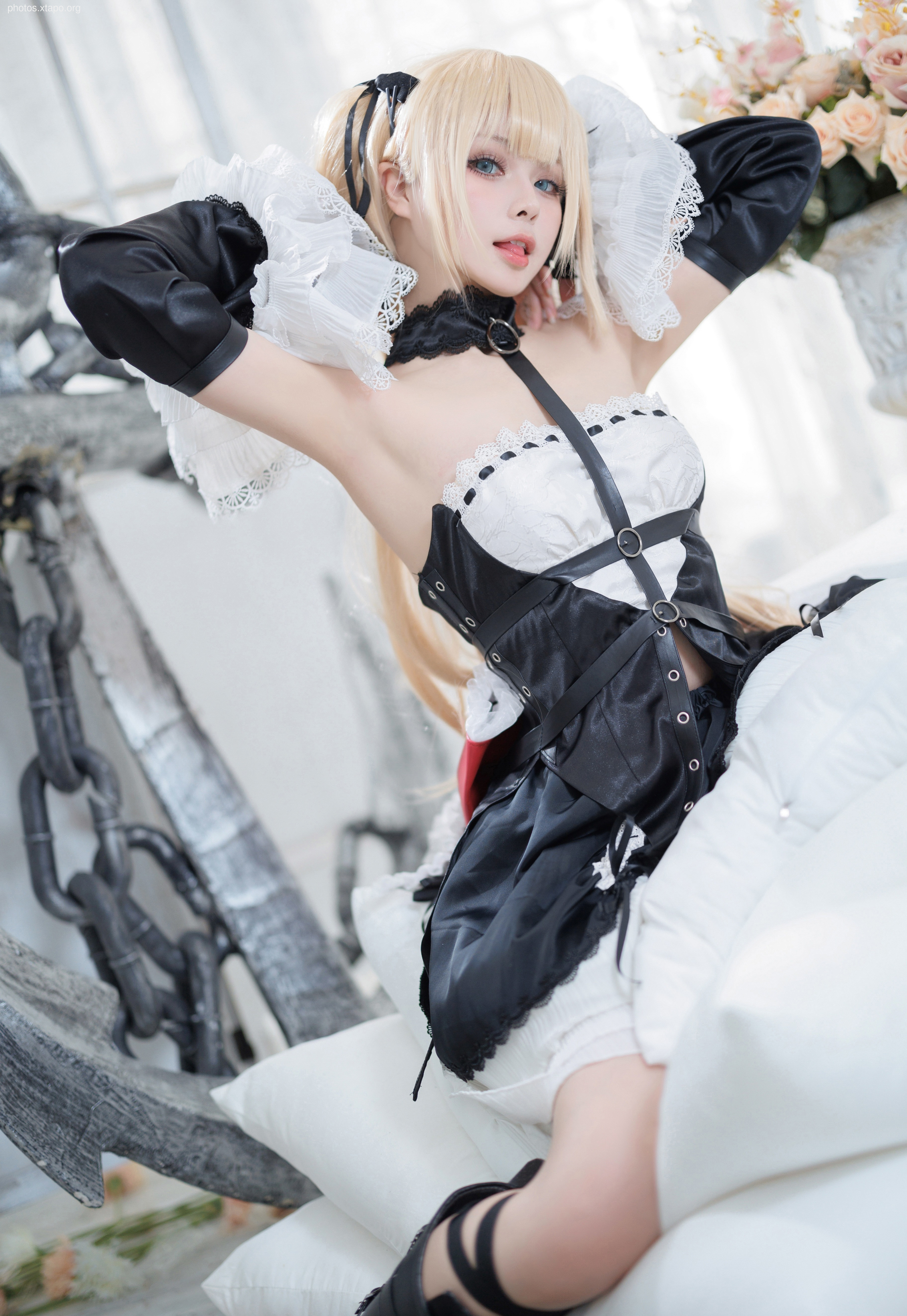Cosplay of a character from the video game Guilty Gear Strive.  The model is posing in a black and white costume with accessories.