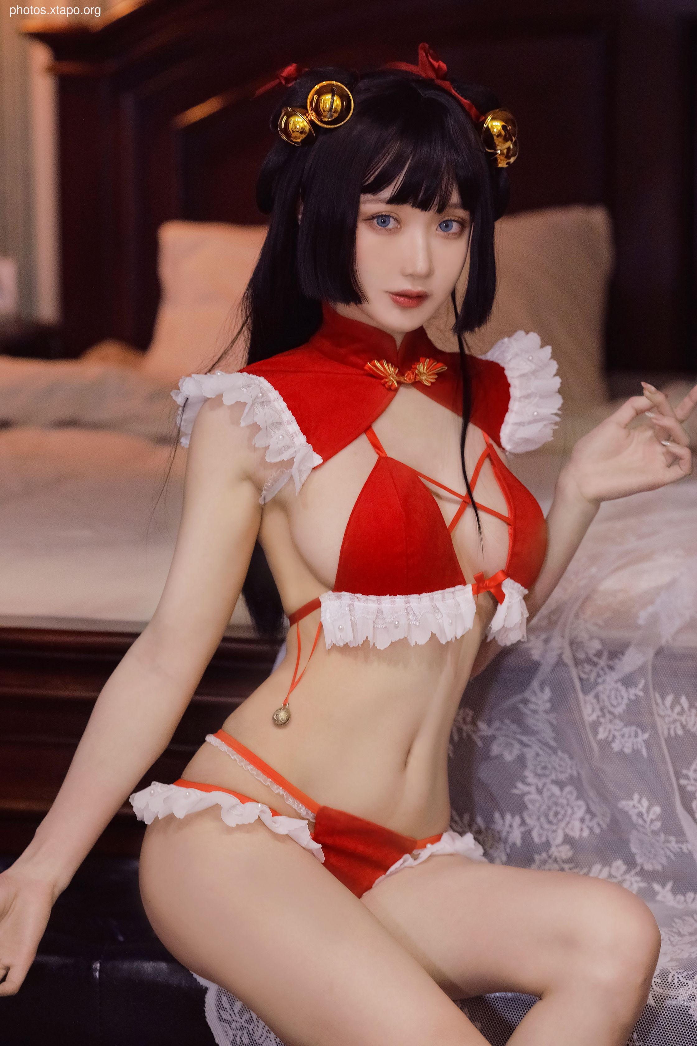 A model poses in a red Chinese-style cosplay outfit.  The outfit features a red velvet top and matching bottoms with lace trim. The model wears her black hair in a bob with gold hair ornaments.
