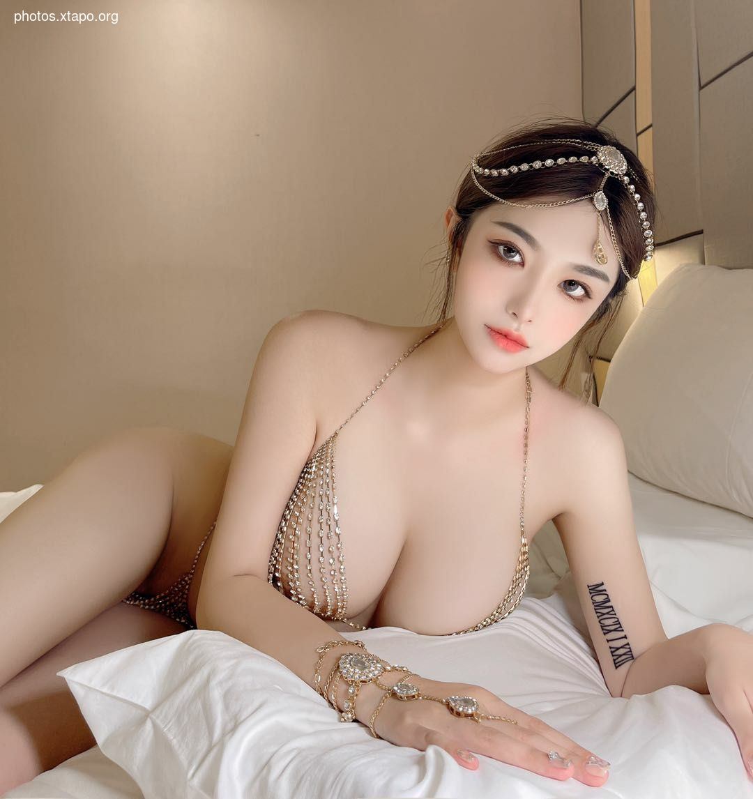 A captivating woman adorned in a dazzling jeweled headpiece and a shimmering chain bra.  The image showcases her beauty and elegance.