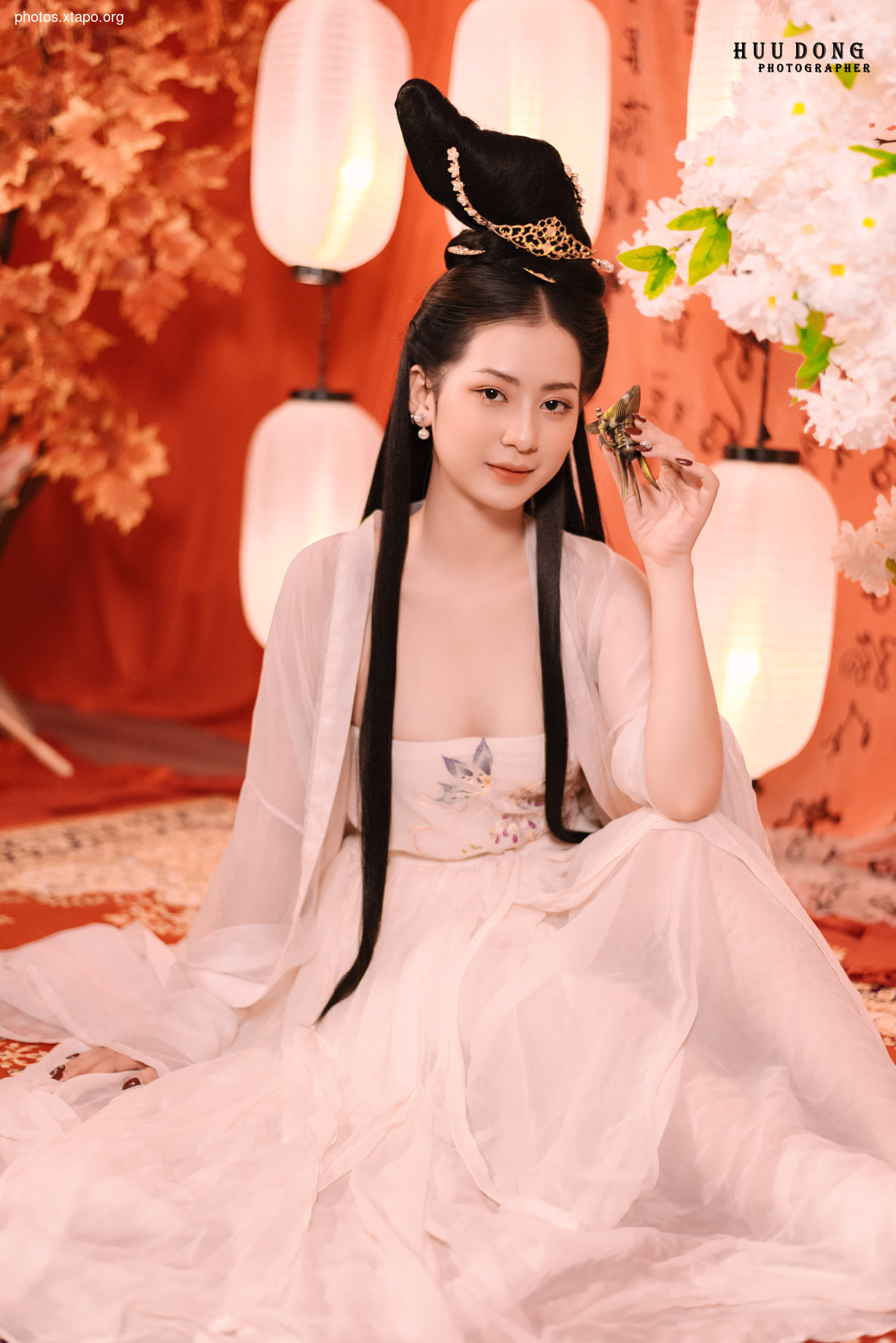 A woman in a stunning traditional Vietnamese áo dài, adorned with intricate details and elegant accessories. The setting is beautifully decorated with oriental-inspired elements. The soft lighting enhances the ethereal beauty of the scene.