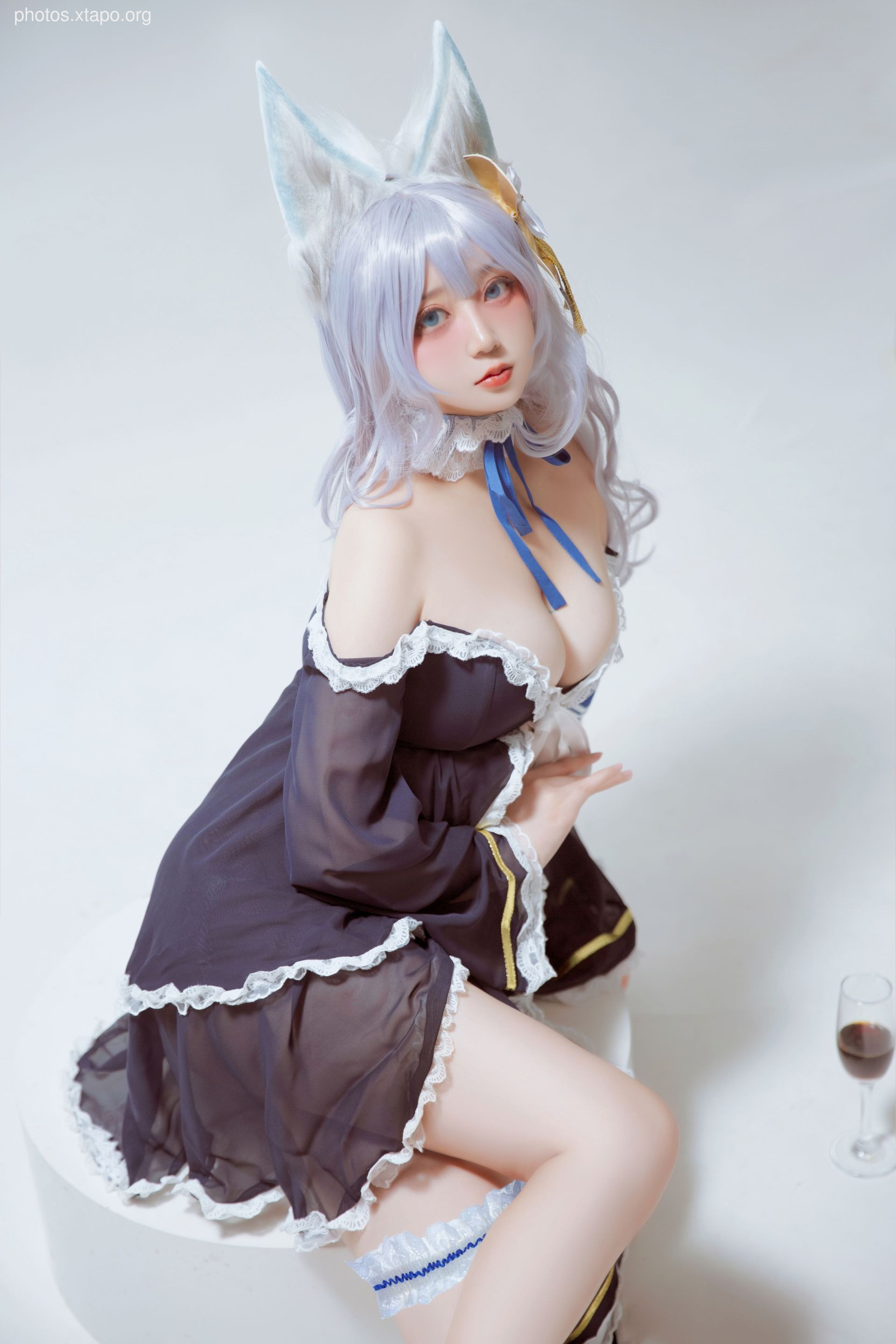 A captivating cosplay of a fox-eared girl in a dark, elegant maid outfit.  The model's pose and costume details are beautifully showcased against a light background.
