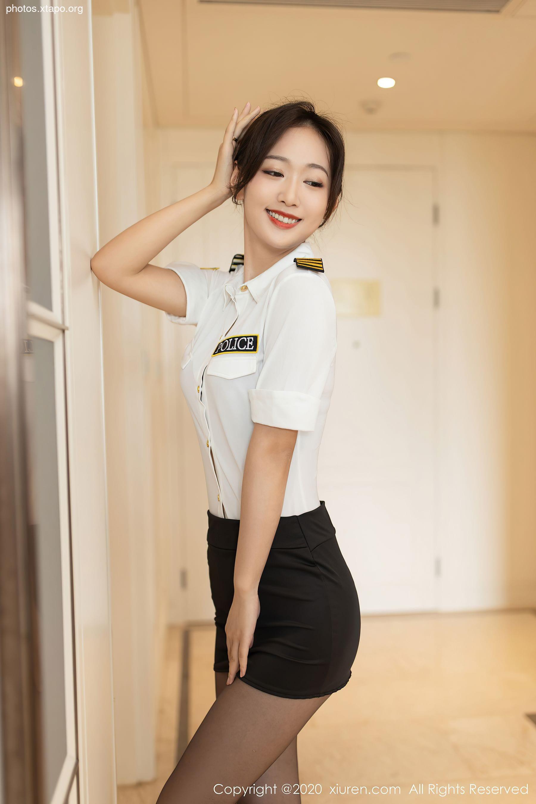 A young woman in a police uniform confidently poses, exuding professionalism and charm.