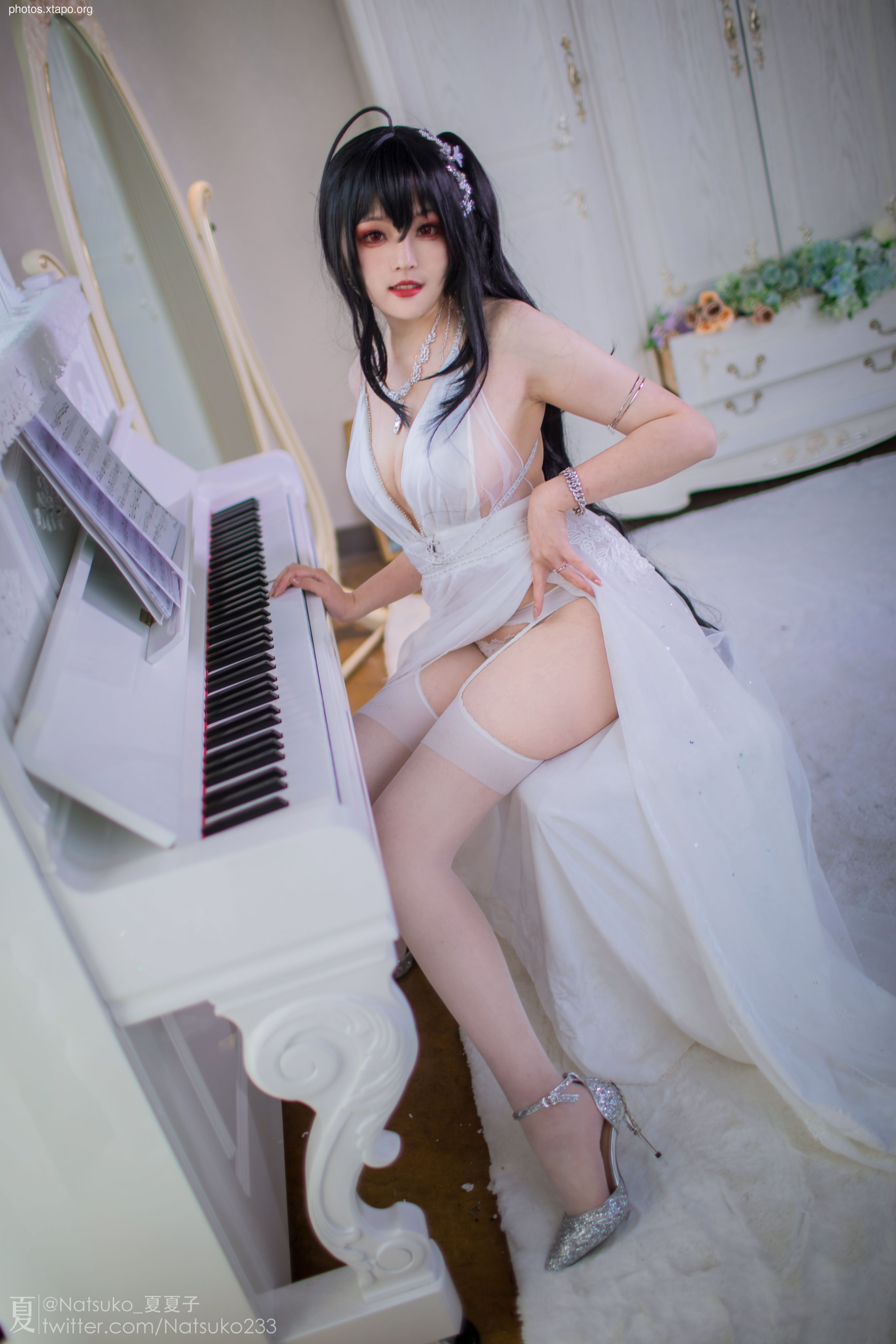 A cosplayer in a stunning white gown sits at a white piano, showcasing an elegant and refined aesthetic.