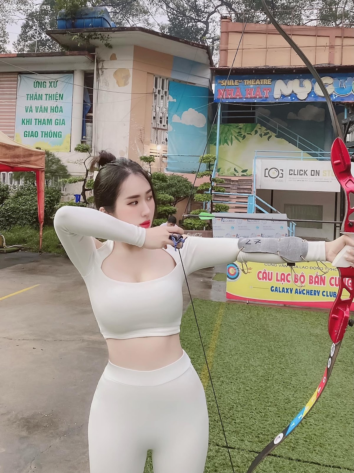 A woman in a white outfit practices archery at Galaxy Archery Club.