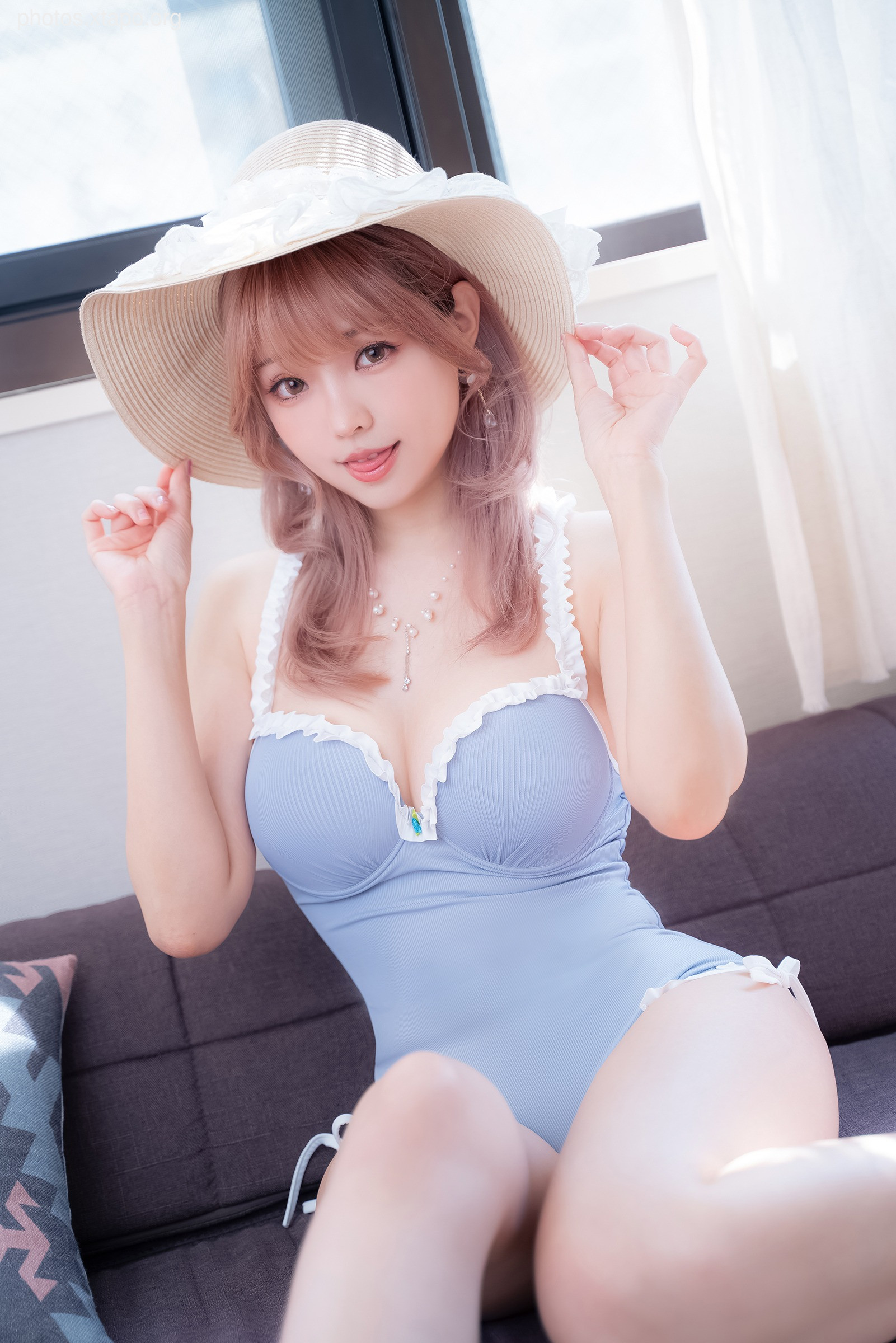 A young woman in a light blue swimsuit and a wide-brimmed hat enjoys a sunny day.