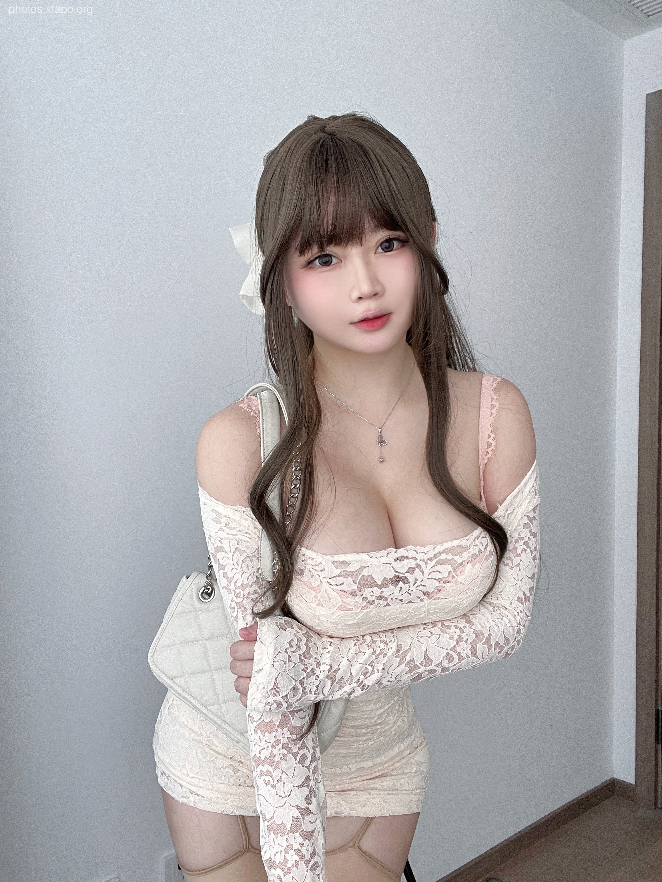 A woman in a beautiful, off-the-shoulder lace dress. She is carrying a stylish handbag and looks very sophisticated.