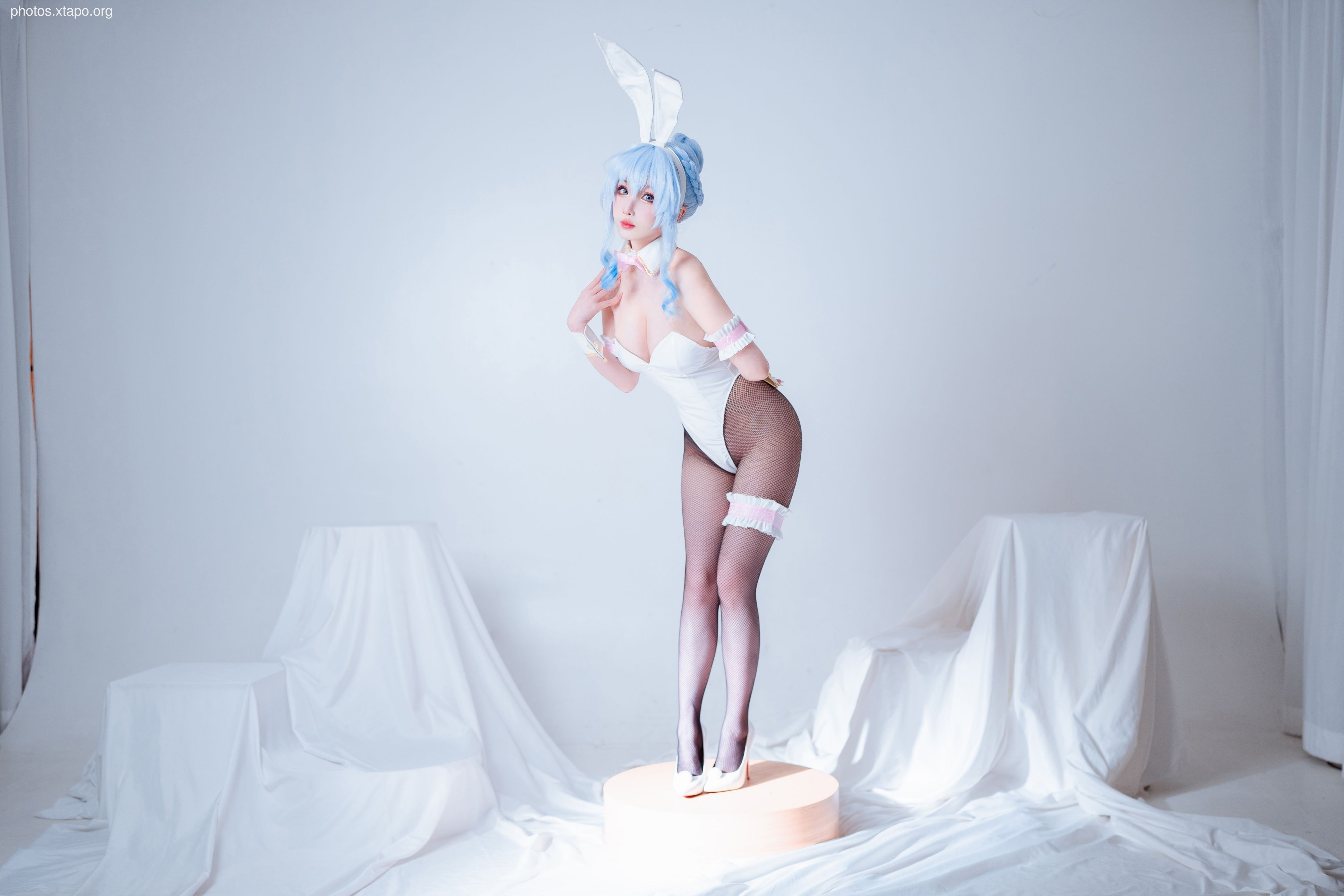 A woman in a white bunny girl costume poses for a photo.