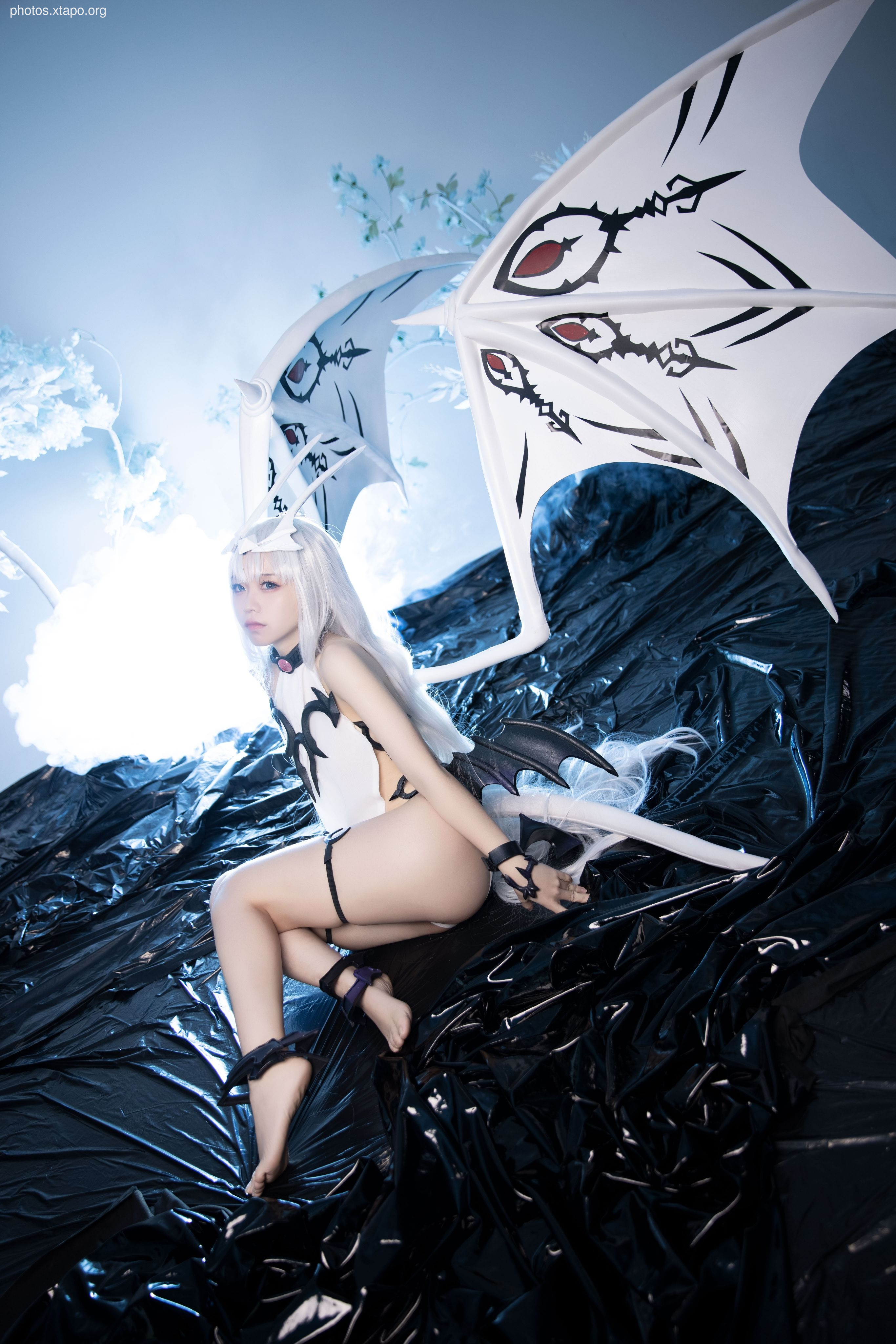 A stunning cosplay of a fallen angel, complete with dramatic wings and a captivating pose.  The model's expression and costume details are beautifully captured.