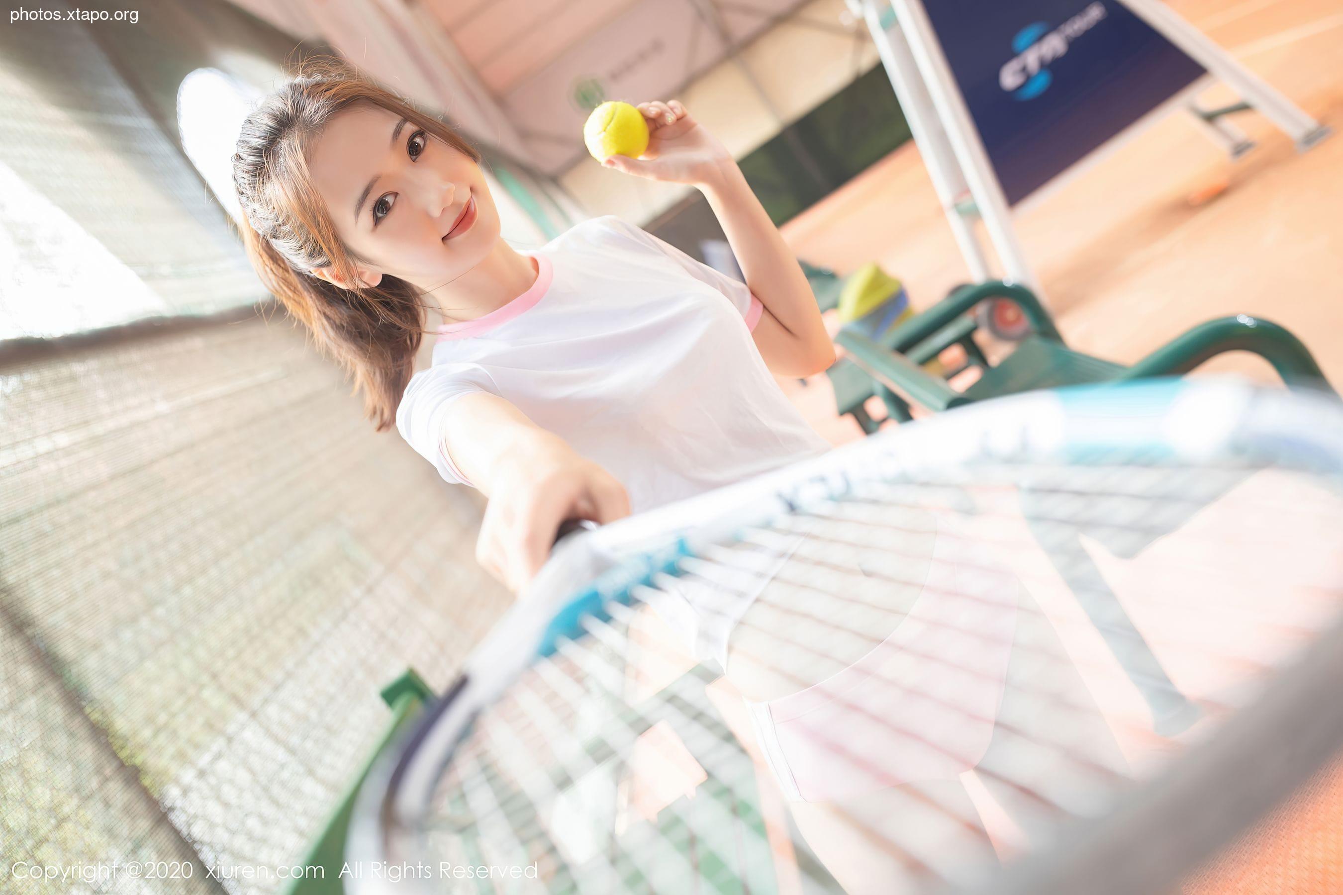 A young woman holds a tennis ball and racket, ready for a game.  She's wearing a white tennis shirt and looks confident and athletic.