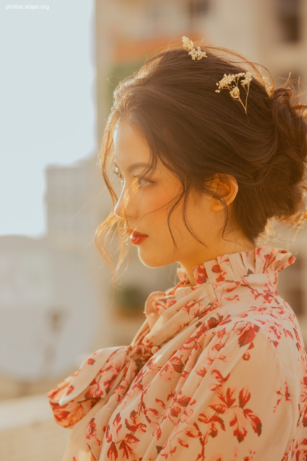 A woman with a sophisticated updo adorned with delicate flowers, wearing a charming floral dress. The warm, golden light enhances her beauty and the overall aesthetic.