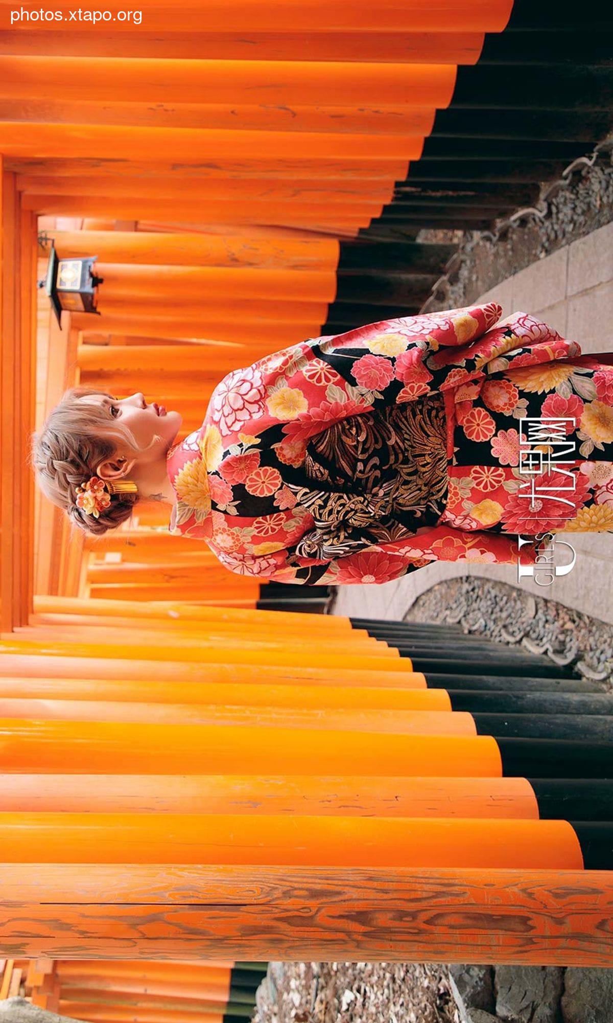 A woman in a vibrant kimono stands amidst the iconic orange torii gates of Fushimi Inari-taisha Shrine in Kyoto, Japan.