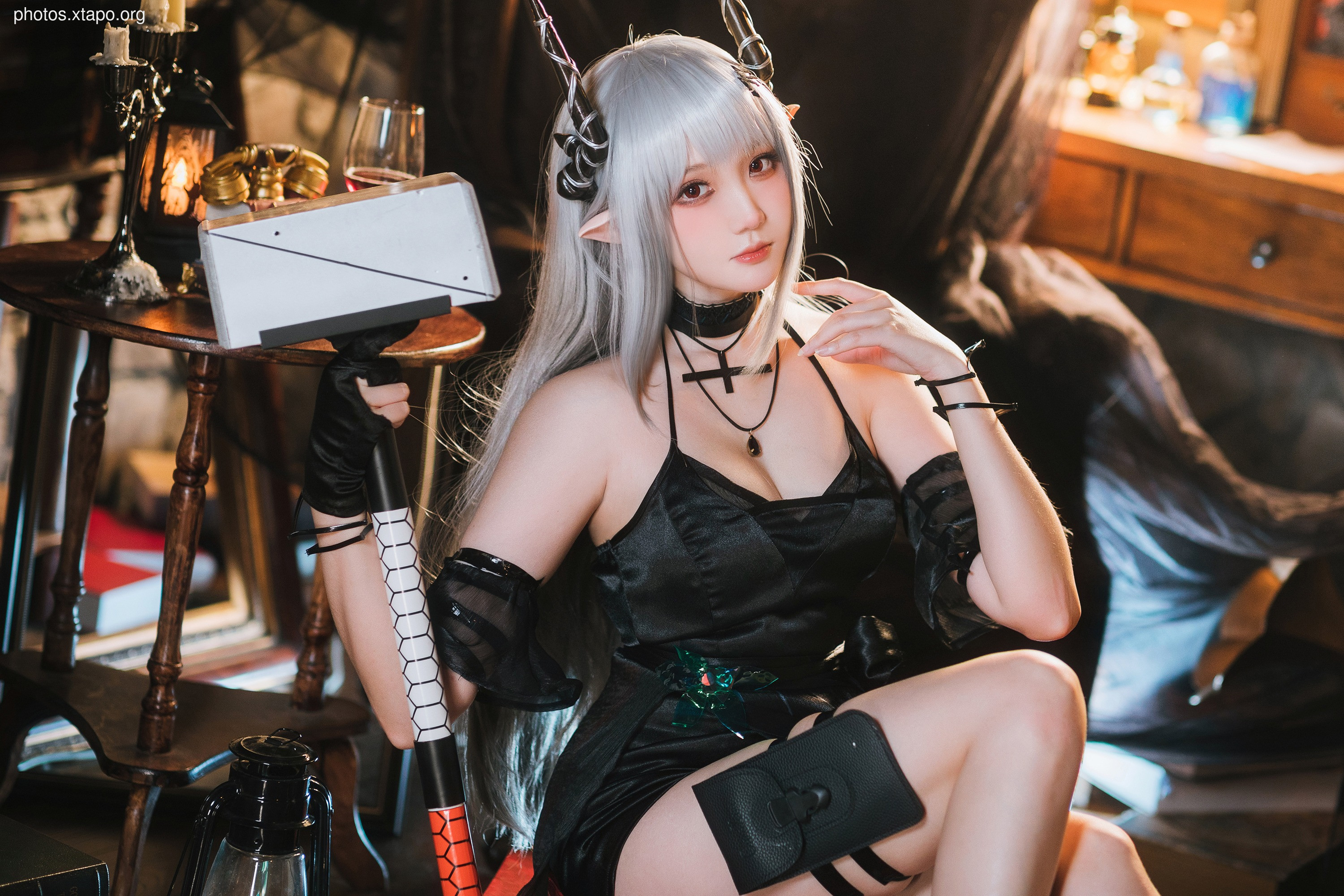 A captivating cosplay portrayal of a devilish maid wielding a unique hammer. The model's striking silver hair, dark attire, and devil horns create a visually stunning and memorable image.