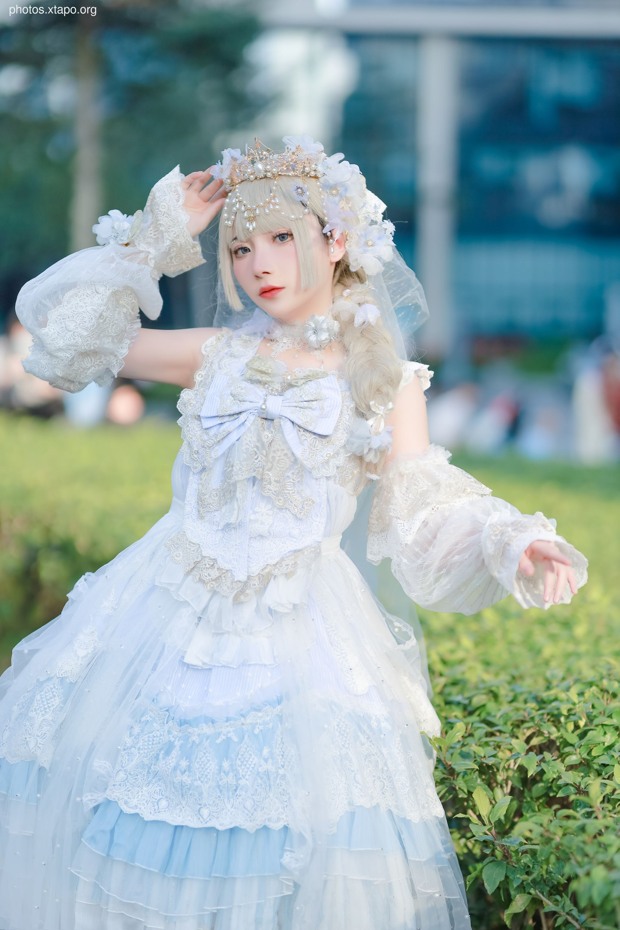 A stunning model in a beautiful light blue and white lolita dress, adorned with lace and intricate details. The dress features a tiered skirt, puffed sleeves, and a delicate crown.