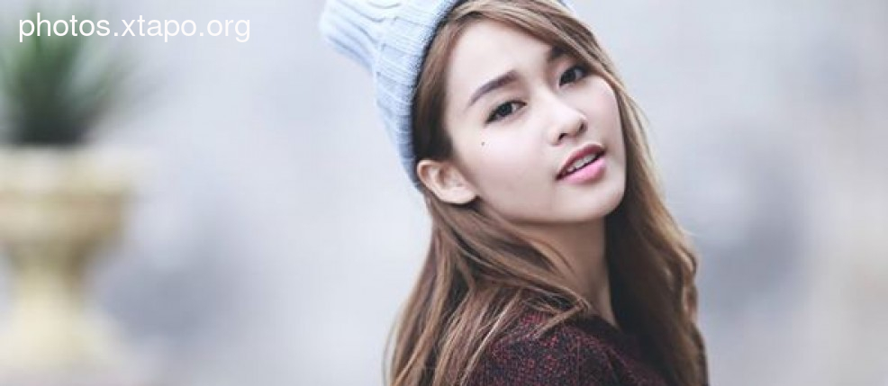 Portrait of a young woman with long brown hair wearing a light blue beanie.