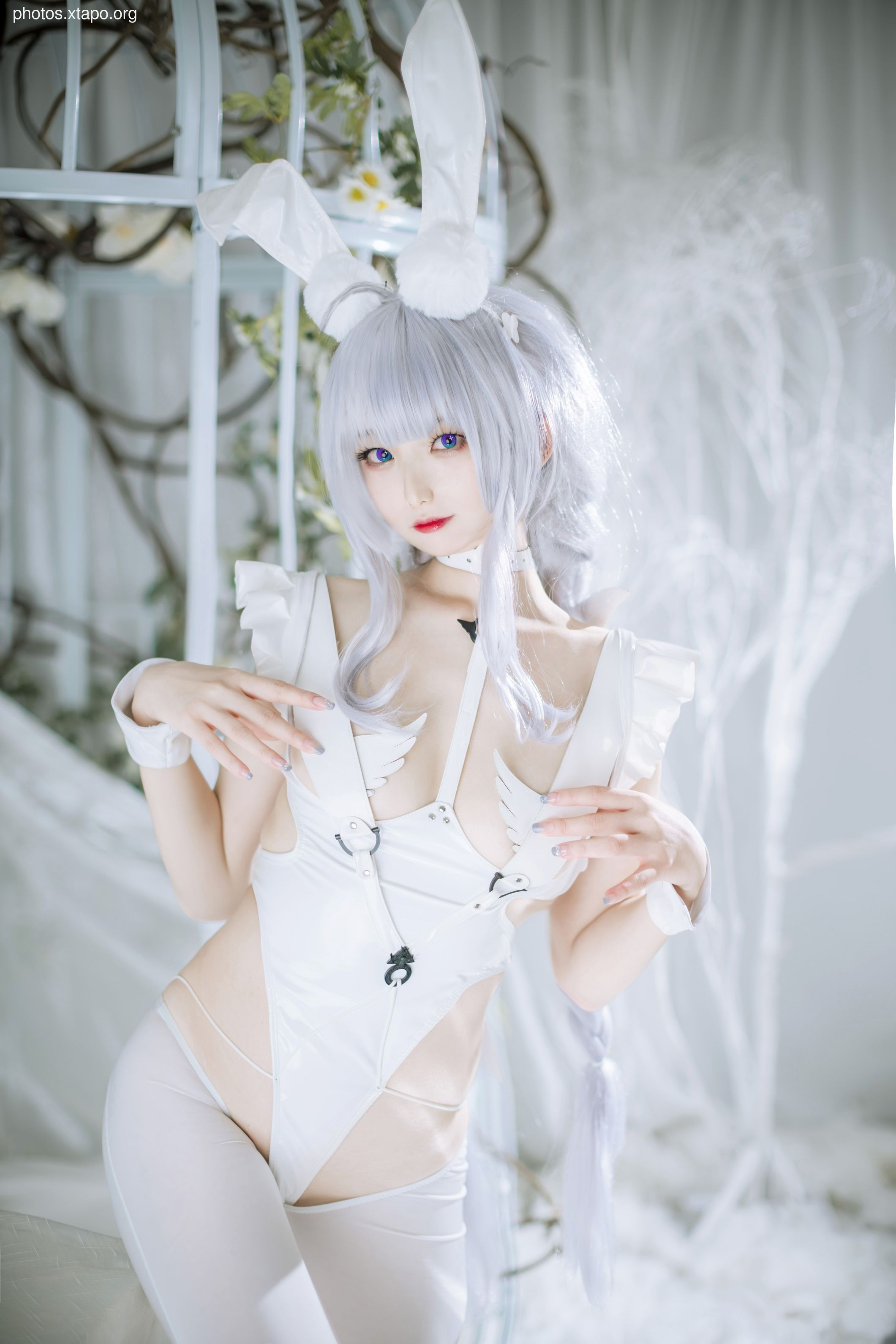 A young woman in a white bunny girl costume poses in a soft, light-filled setting.