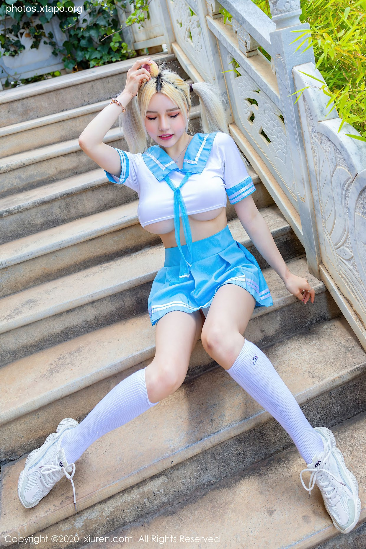 A playful young woman in a schoolgirl uniform sits on a staircase, showcasing a cute and slightly mischievous expression.