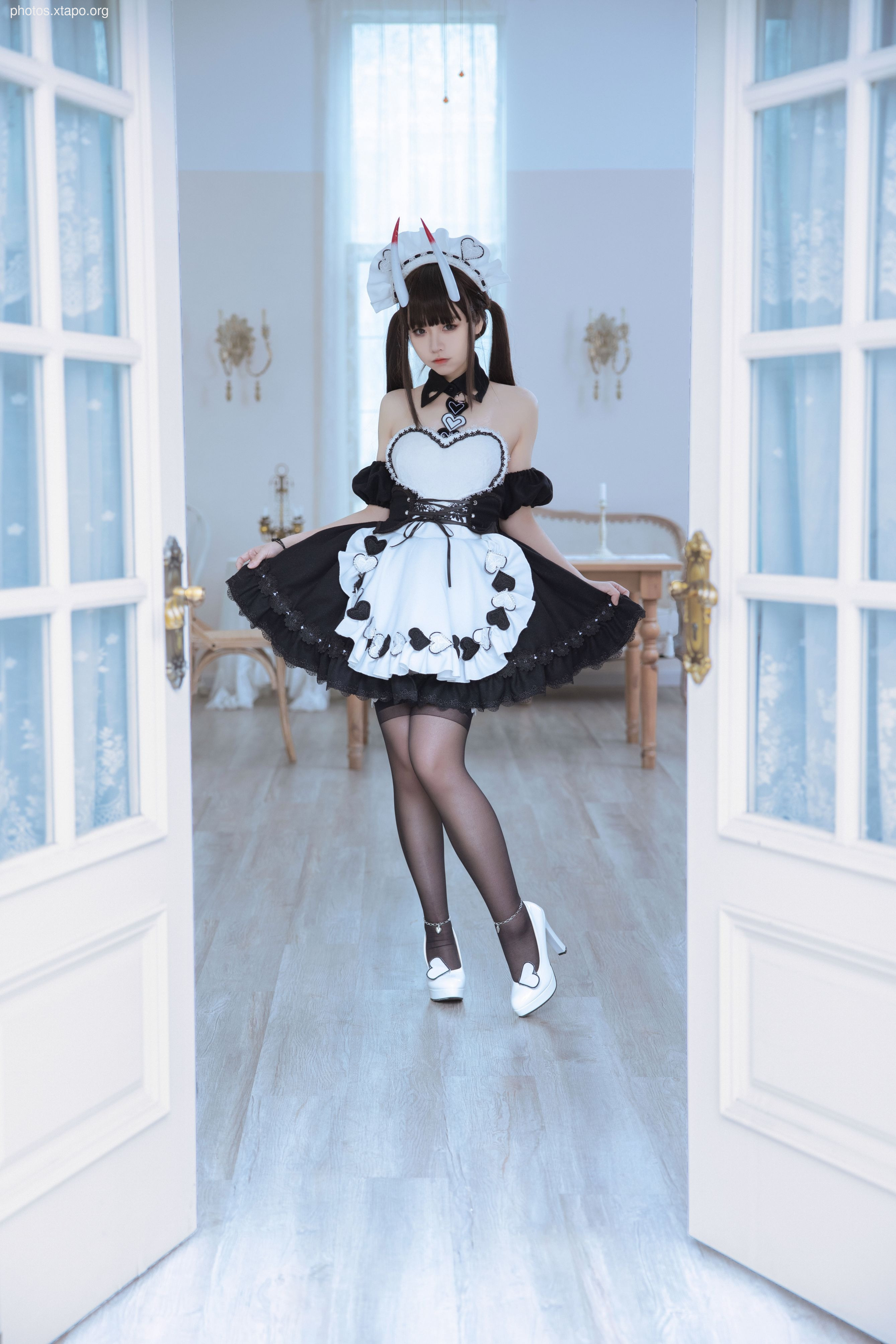 A playful maid in a devilish costume, posing in a bright room.