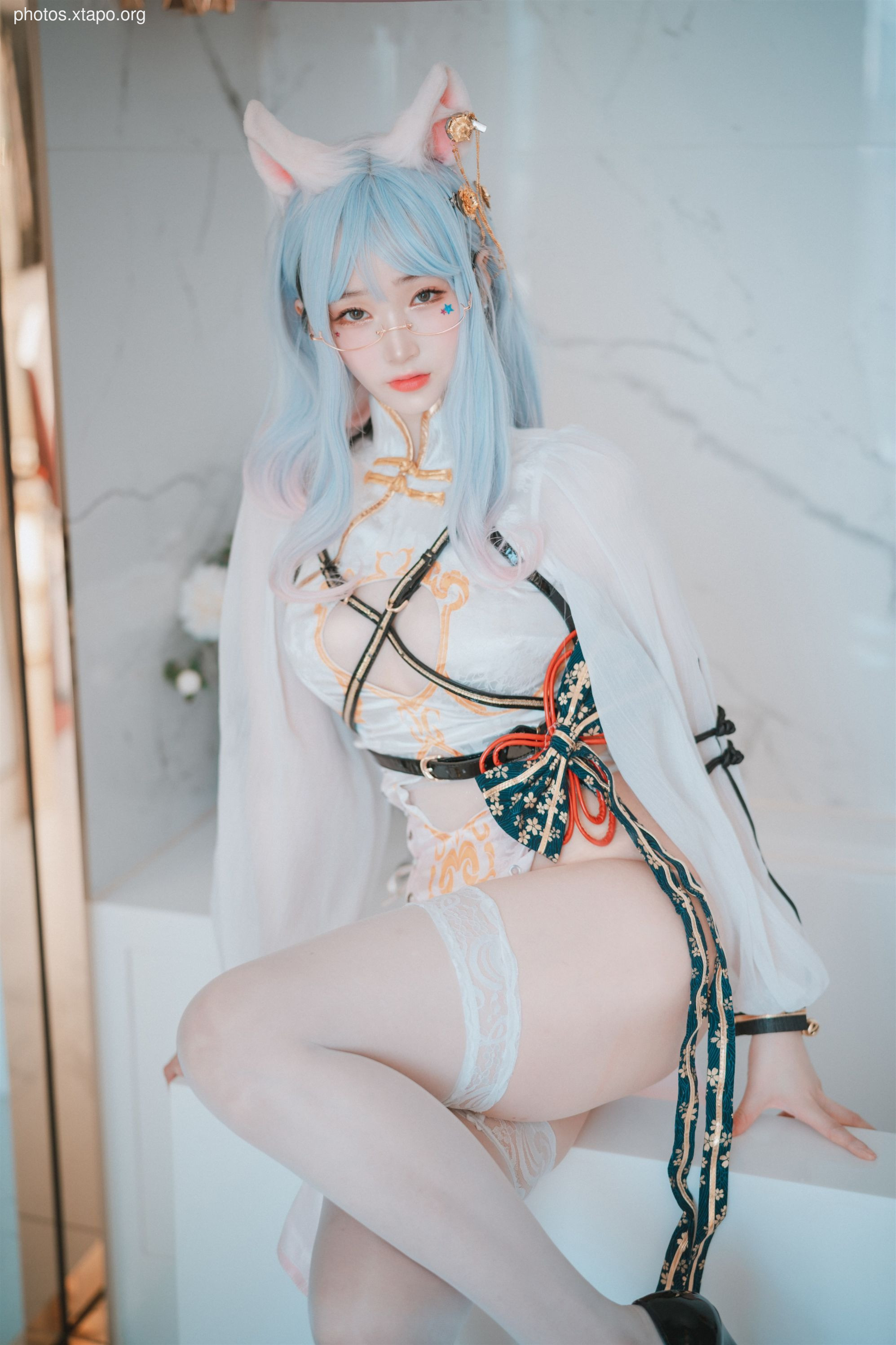 A stunning cosplay model poses in an elegant, white and gold outfit with intricate details and cat ears.  The image showcases the model's captivating expression and the exquisite craftsmanship of the costume.