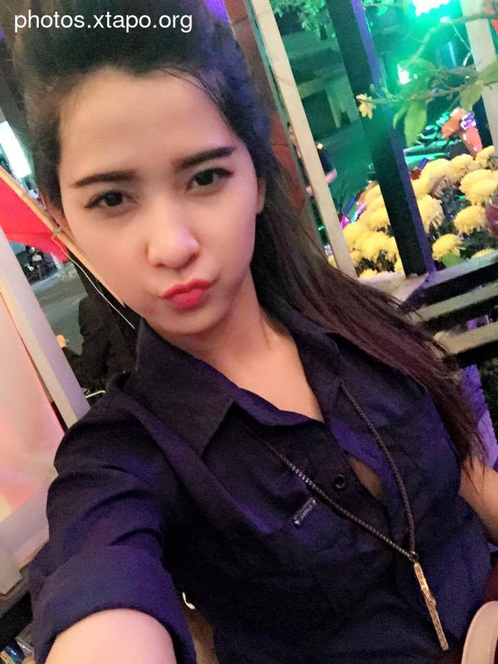 A young woman poses for a selfie at night, wearing a dark purple shirt.