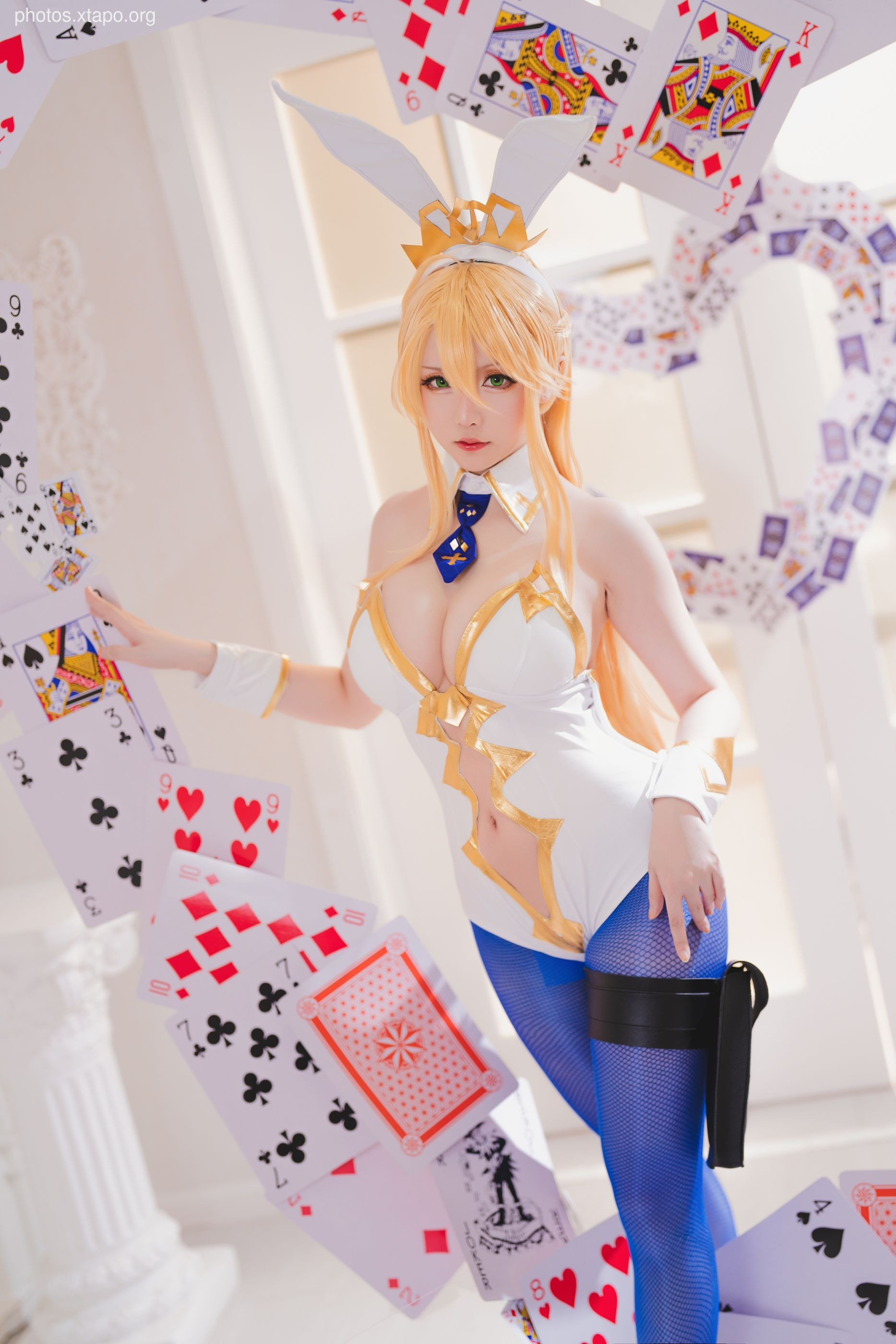 A stunning cosplay of a bunny girl surrounded by playing cards. The model's costume is intricate and detailed, and her pose is captivating.  The image is well-lit and the overall aesthetic is high-quality.