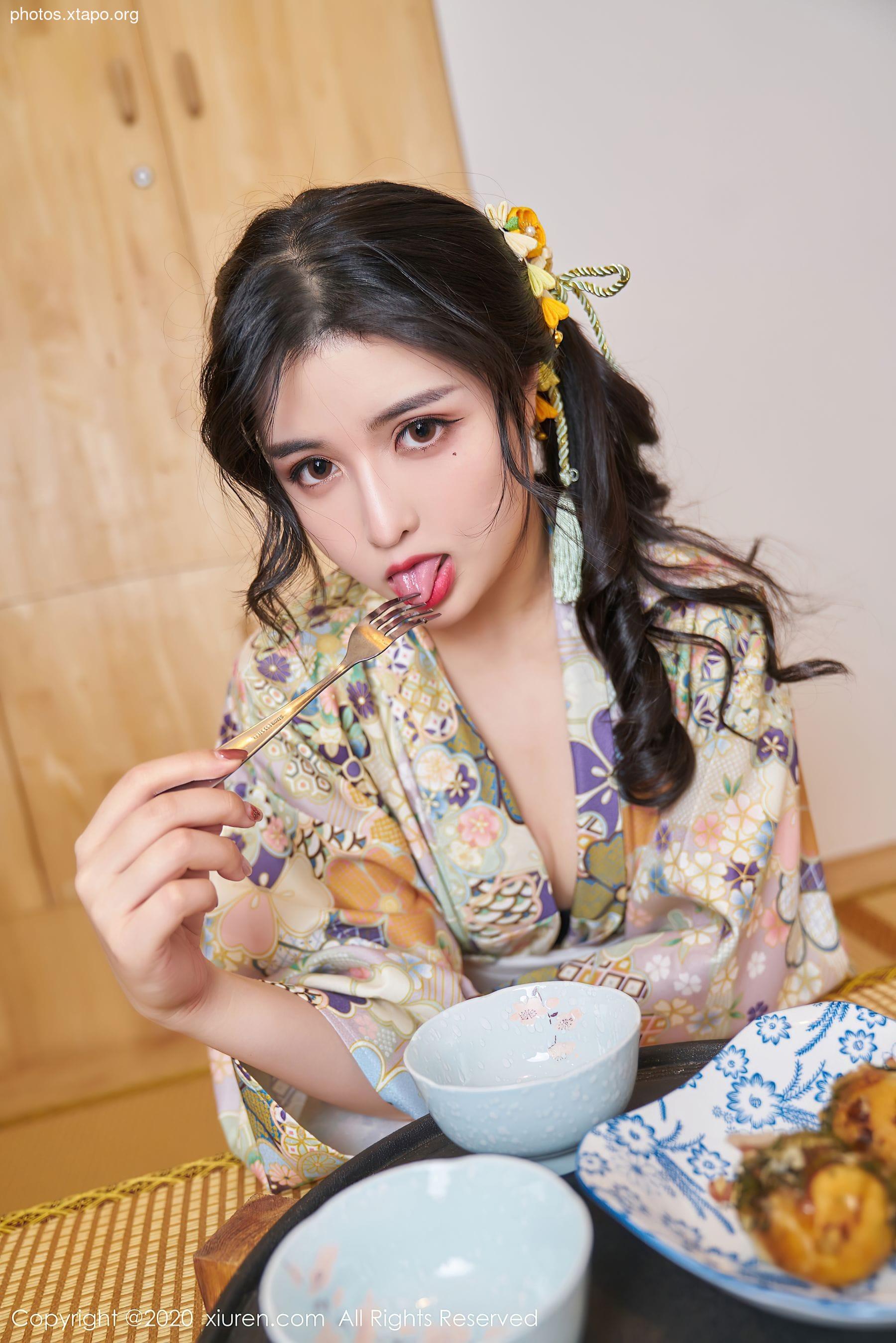 A woman in a kimono playfully eats with a fork.