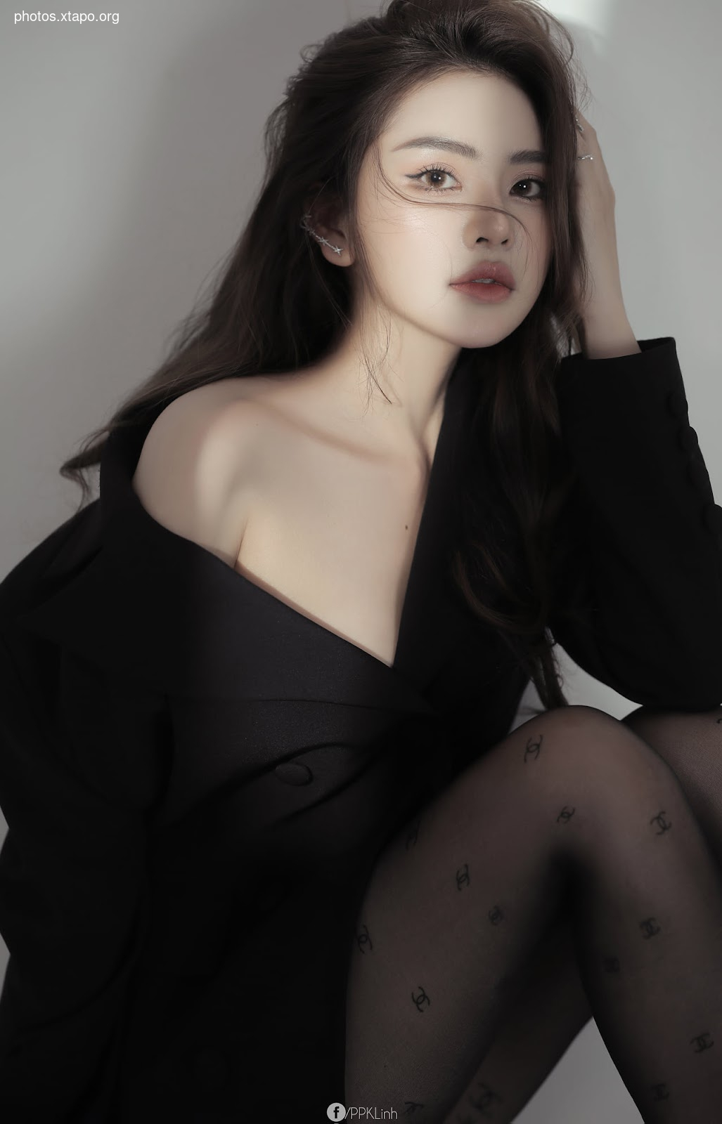 A stylish woman poses in a black off-the-shoulder top and patterned tights. The image is shot against a neutral background, highlighting her beauty and fashion sense.