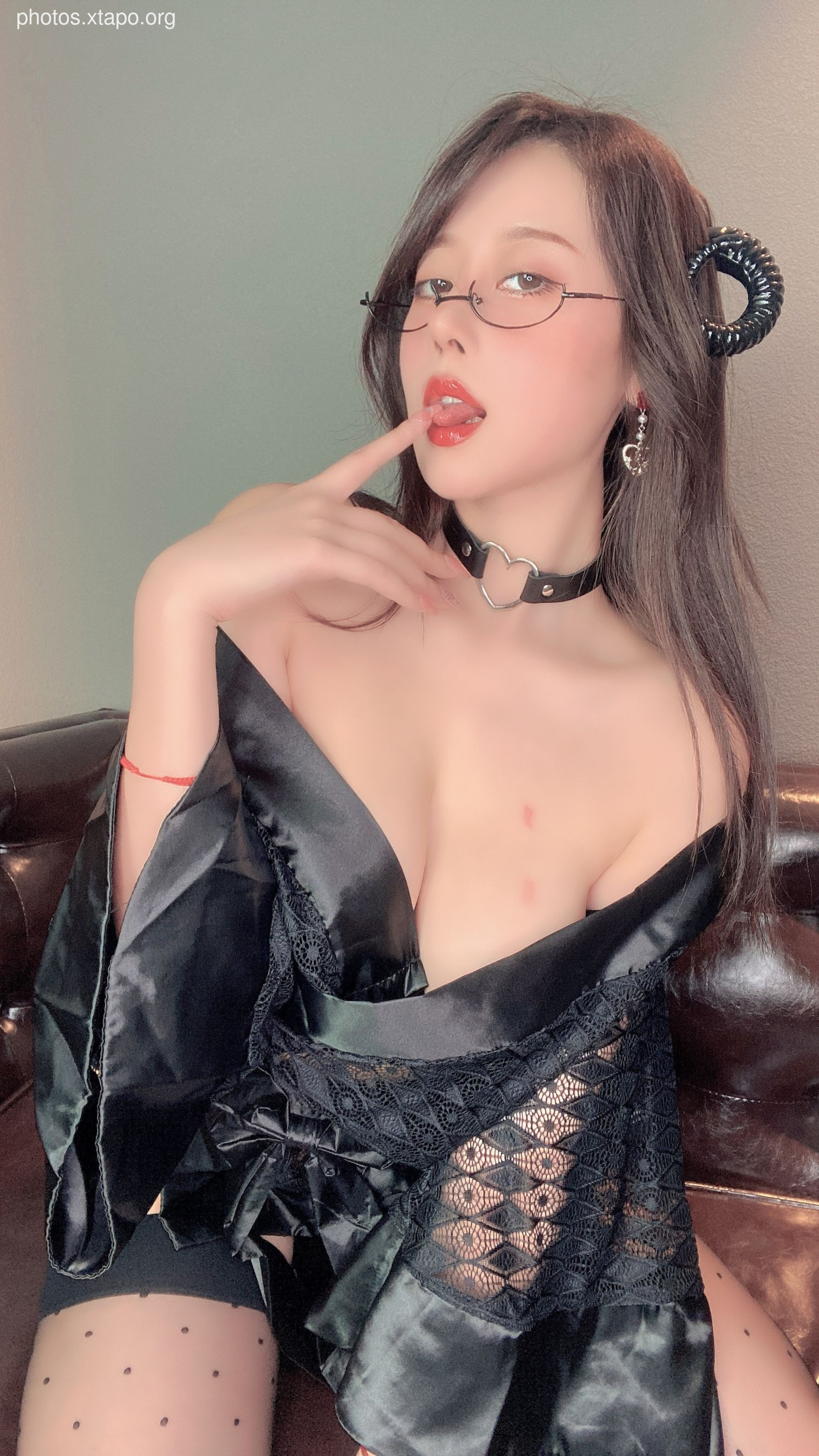 A playful and seductive woman in a black lace outfit with devil horns.