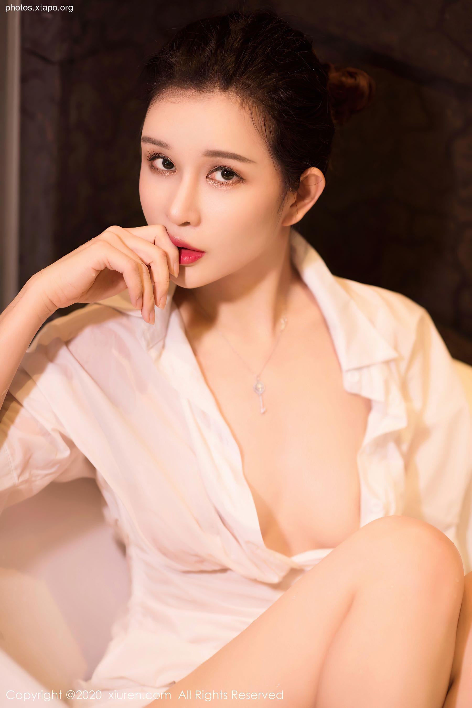 A young woman poses in a white shirt, showcasing her beauty and elegance.