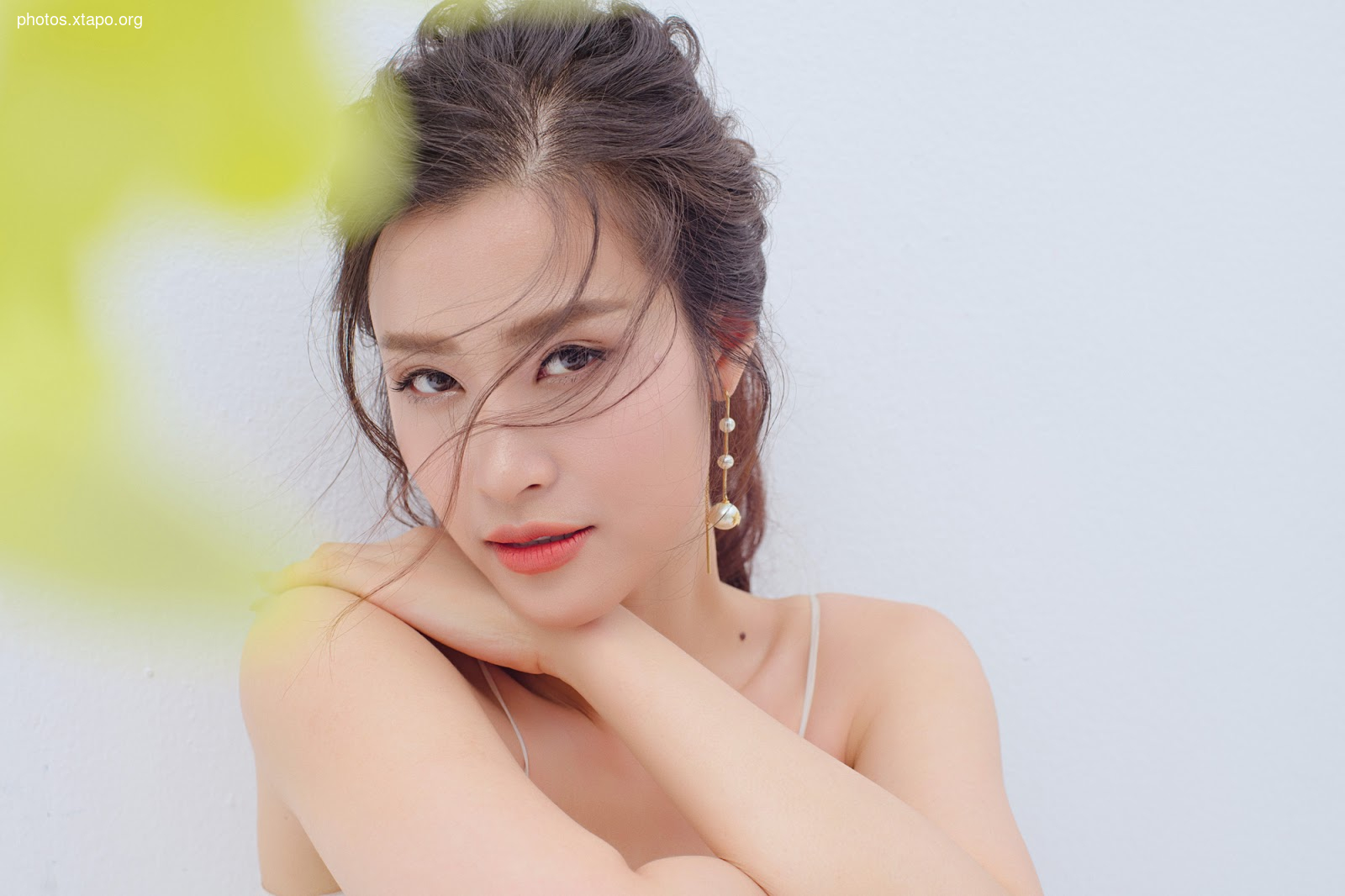 Close-up portrait of a young woman with her hair styled up. She's wearing delicate earrings and has a soft, natural makeup look.