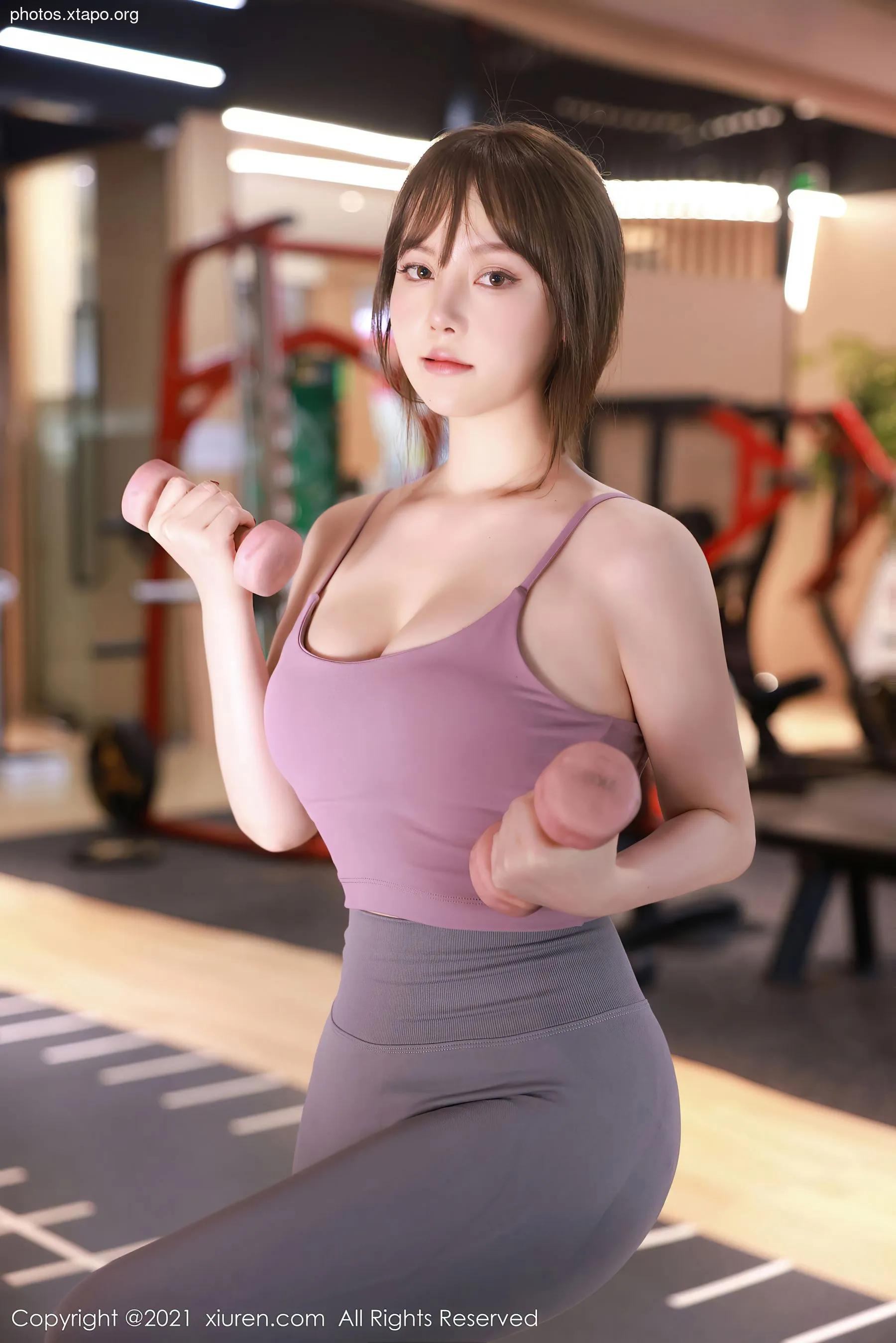 A woman works out at the gym using dumbbells.