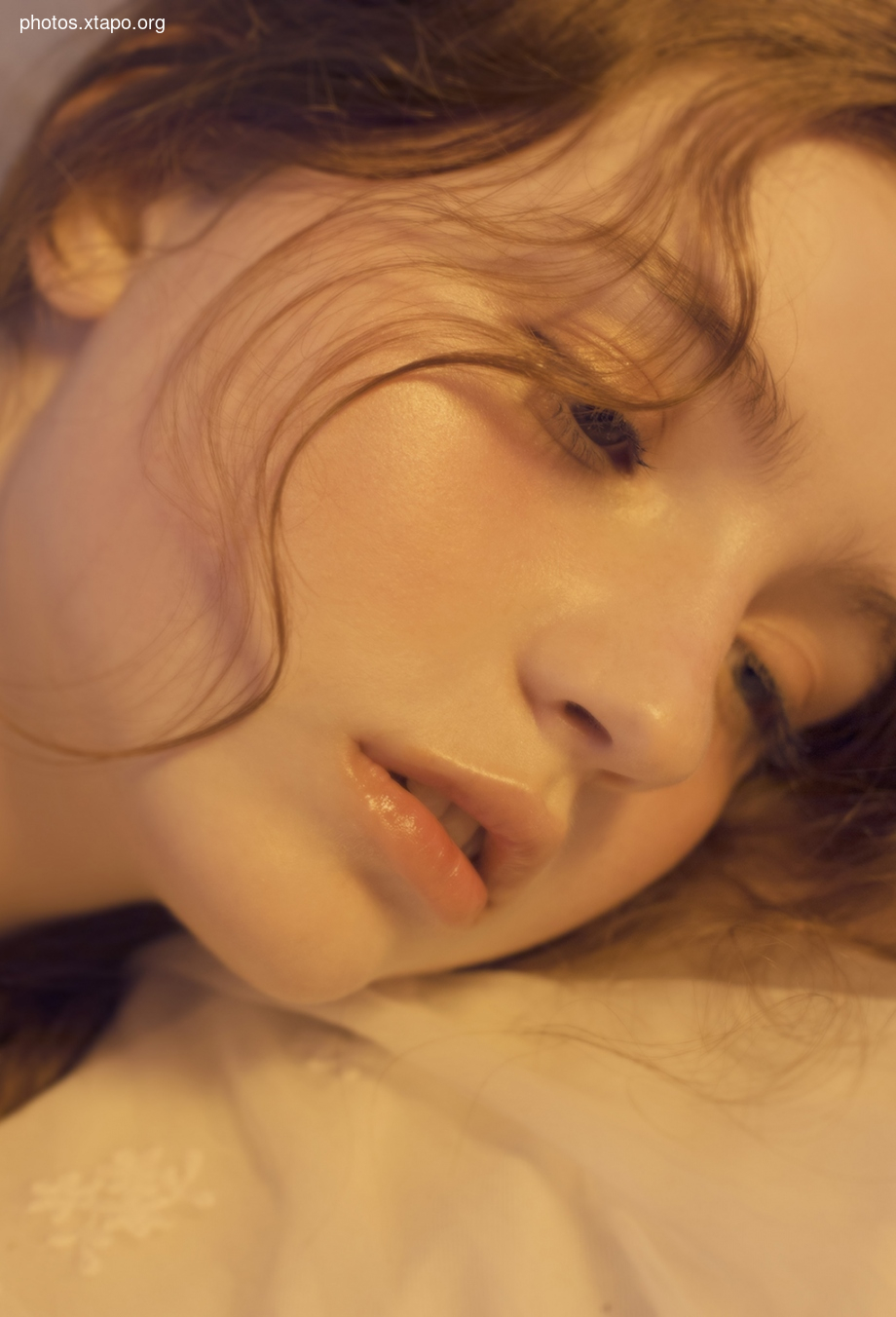 Close-up of a woman's face, bathed in warm, golden light. Her hair is loose and flowing, her expression serene. The image evokes a sense of calmness and beauty.