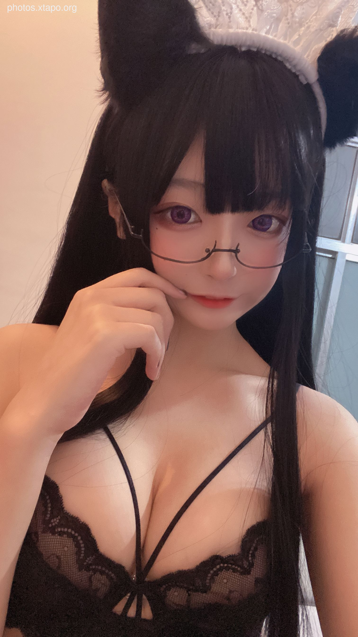 A young woman cosplaying as a maid, wearing a black lace bra and glasses.  She has dark hair and cat ears.