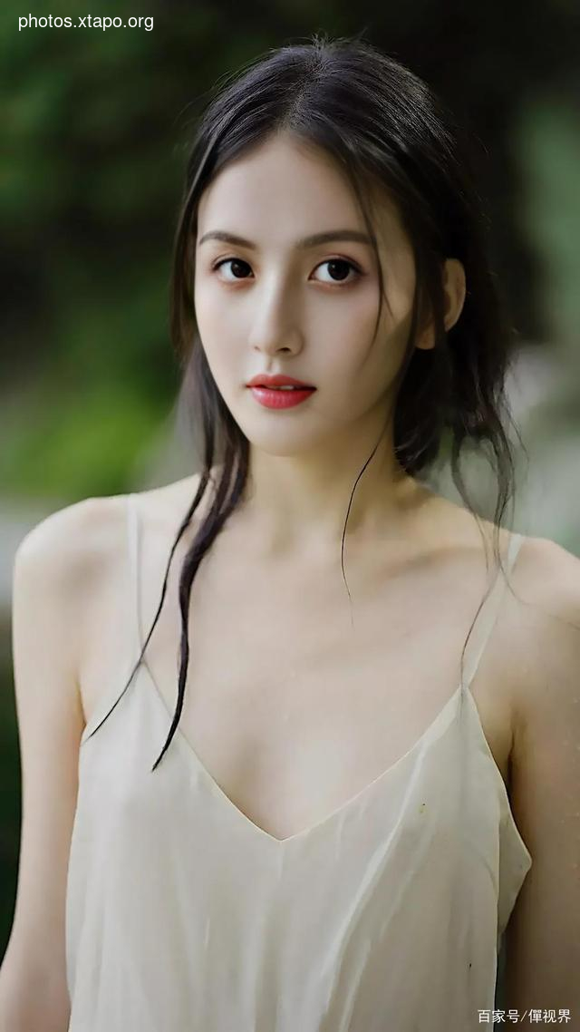 Portrait of a young woman with long dark hair wearing a white slip dress. She is looking at the camera with a soft expression.